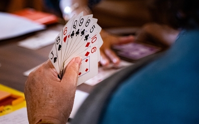 Personne âgée qui tient un jeu de carte avec sa main gauche