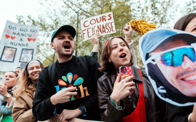 Un jeune homme et une jeune femme encouragent bruyamment des coureurs. A l'arrière plan, une pancarte "Cours feignasse". 