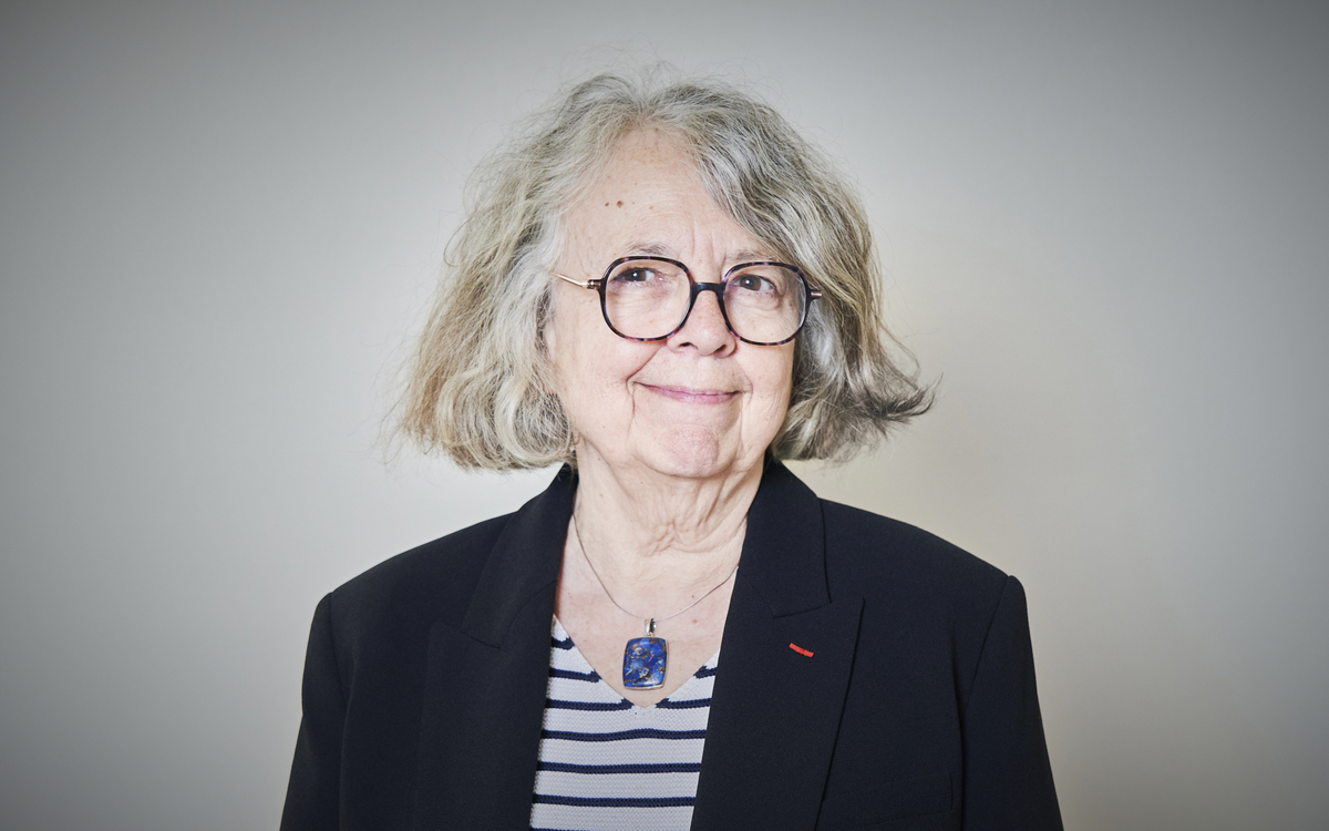 Portrait d'Agnès Bertrand avec lunettes marrons veste bleu marine et tee-shirt marin avec collier et pendentif bleu