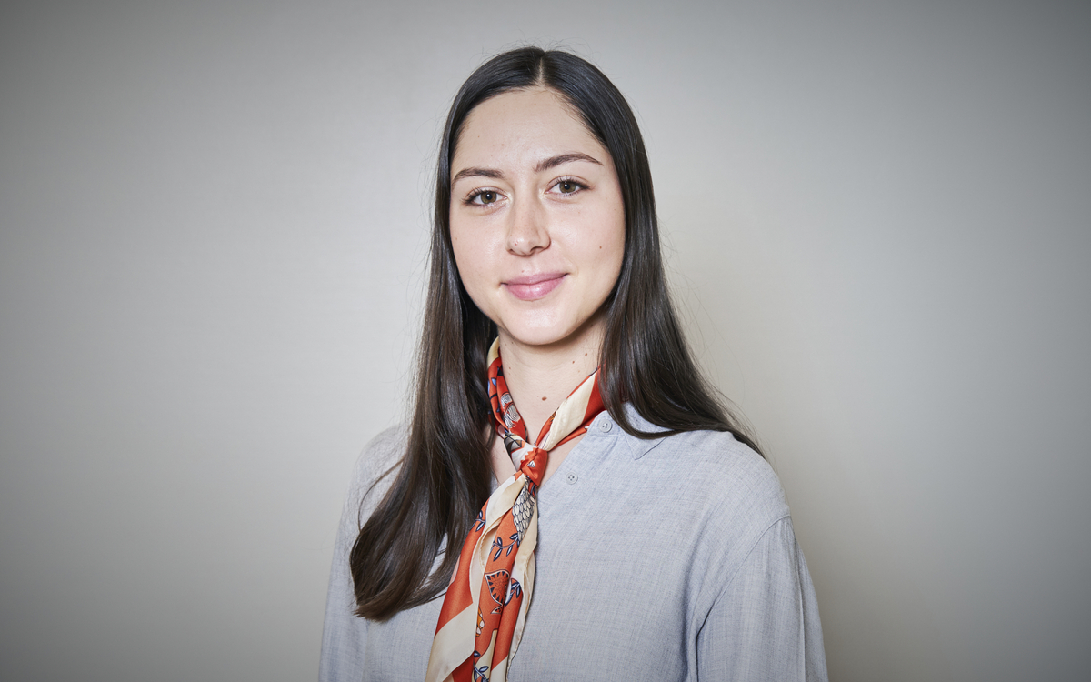Portrait de Chloé Battault en chemise gris clair avec foulard multicolore dans les tons orangées et crème