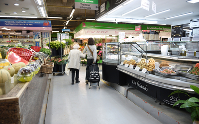 Une personne accompagnée d'une personne âgée dans les allées du marché couvert des Batignolles (17e).