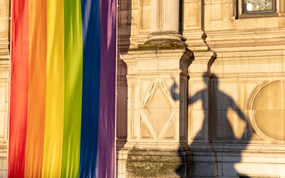 L'hôtel de ville aux couleurs LGBTQI+ et une ombre de statue sur la façade. 