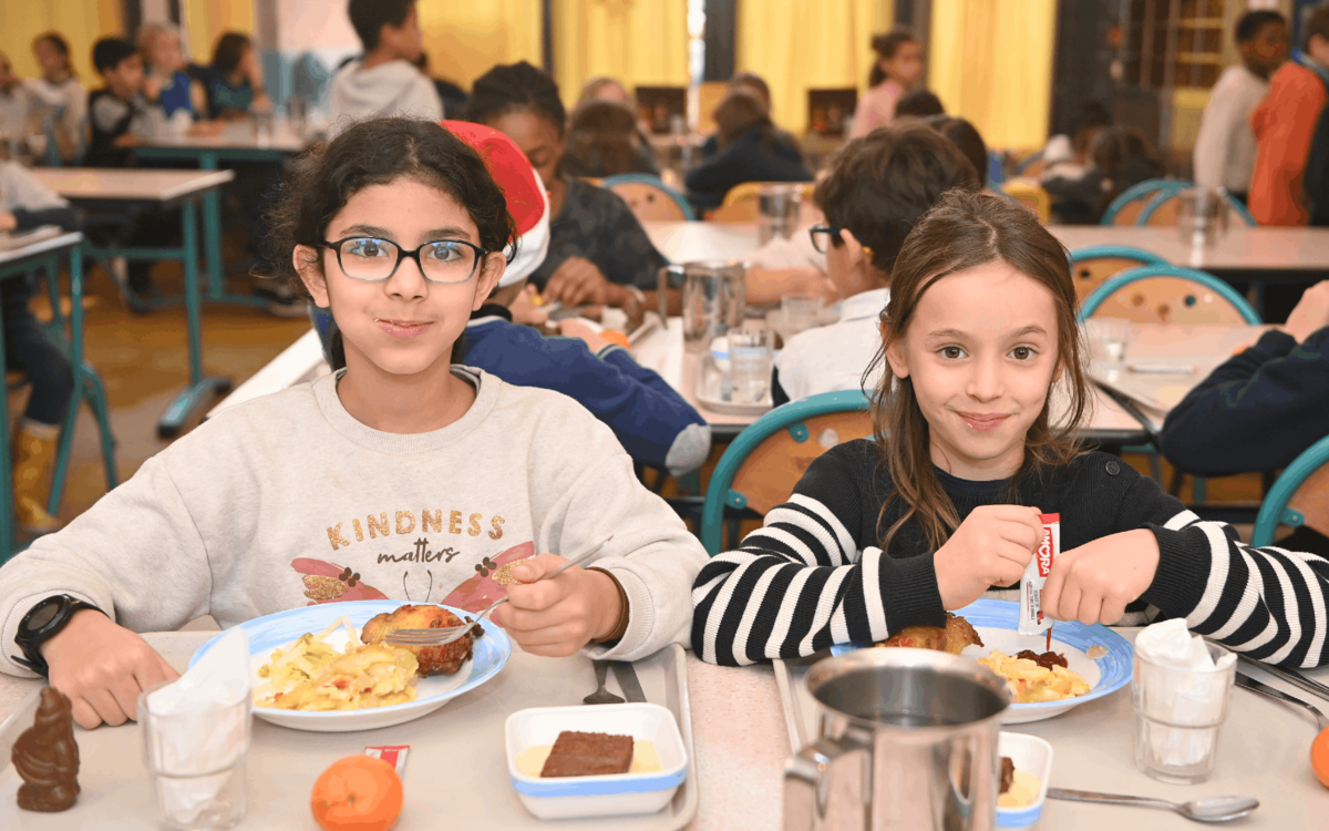 deux enfants mangent à la cantine