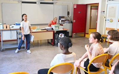 une collégienne est debout face à ses camarades assis dans une salle de classe pour réciter son discours