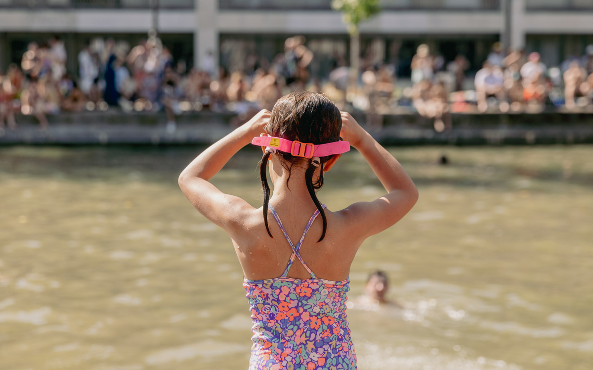 Une enfant se pare de ses lunettes de natation avant une baignade dans le canal Saint Martin. 