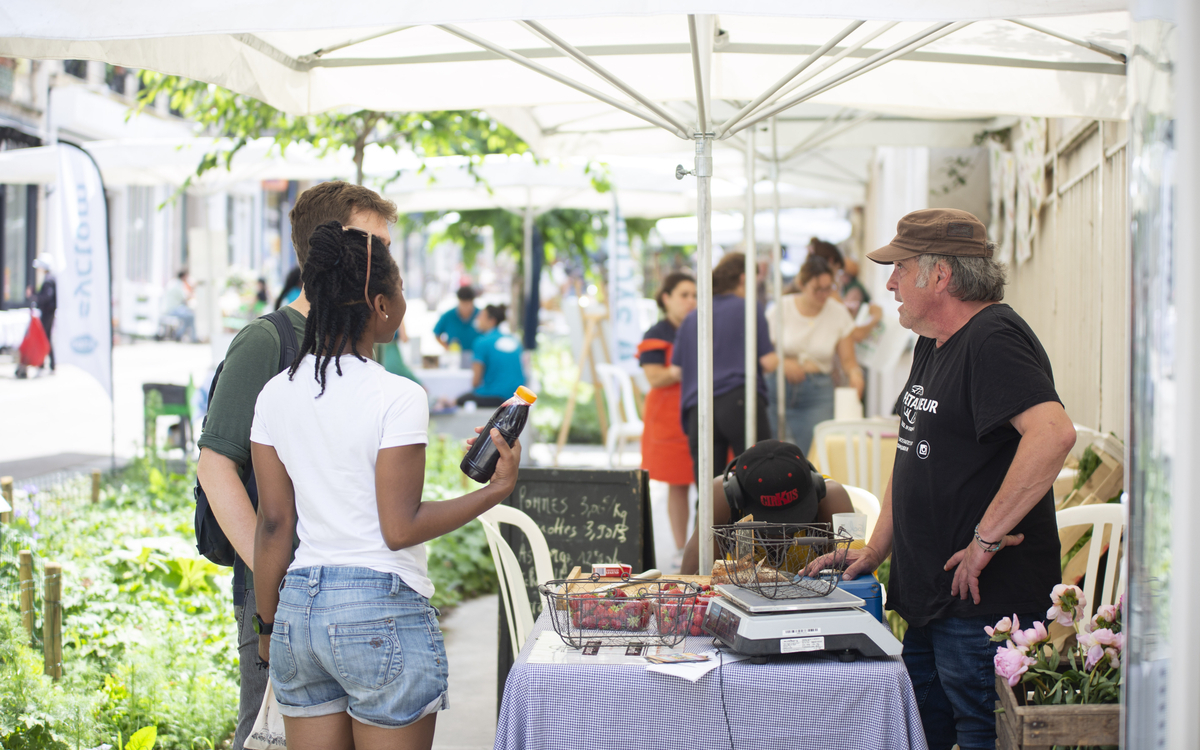 des personnes discutent avec un commerçant du marché du 18e durable
