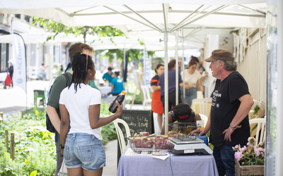des personnes discutent avec un commerçant du marché du 18e durable