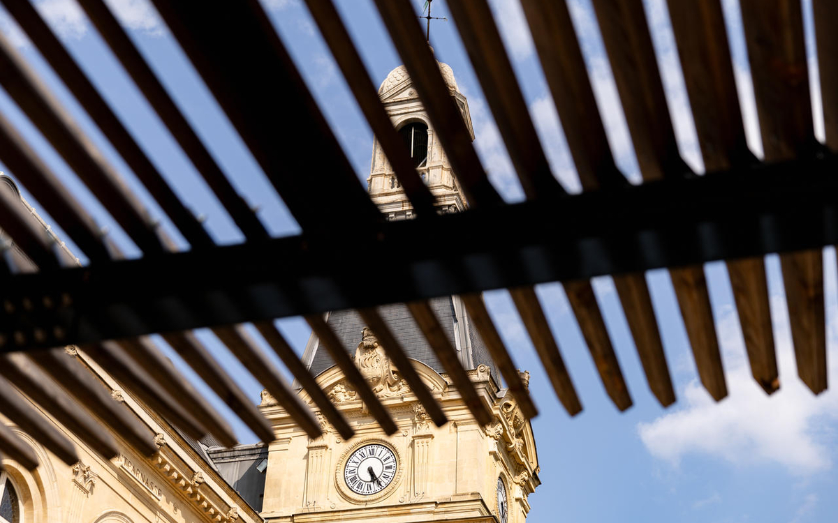 Aperçu du toit de la mairie du 14e à travers les raies d'une ombrière
