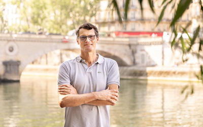 un homme les bras croisés devant la Seine