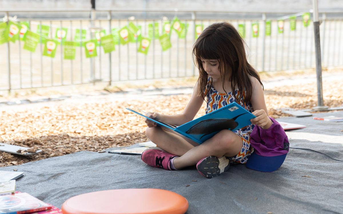 Une fille lit un livre à l'ombre en extérieur