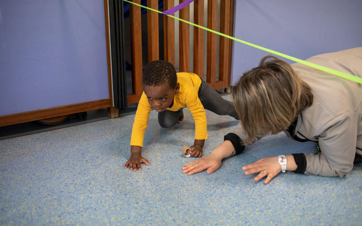 un enfant joue avec une professionnelle en crèche