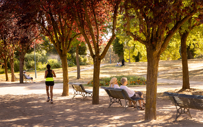 Coureuse et personnes se reposant sur des bancs du Le parc de la Butte-du-Chapeau-Rouge.