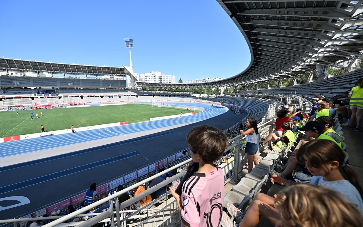 Des enfants des centres de loisirs assistent à un match de football depuis les tribunes et encouragent les athlètes.