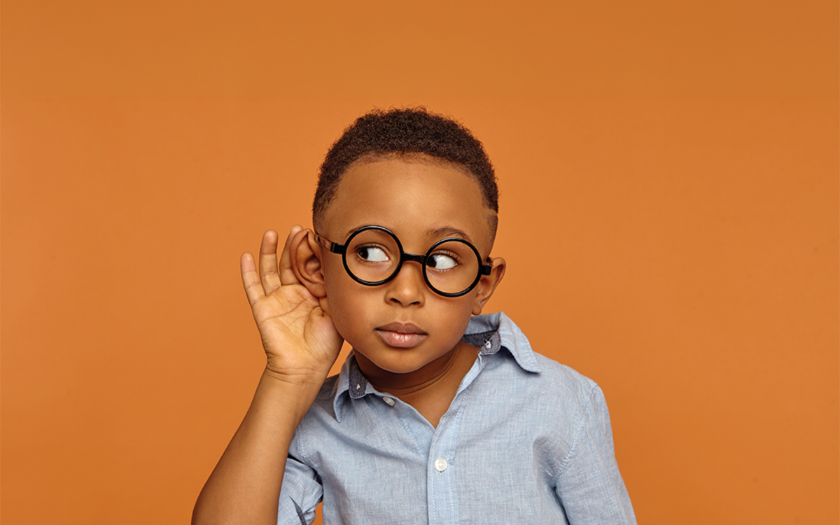 Un petit garçon à lunettes tend l'oreille