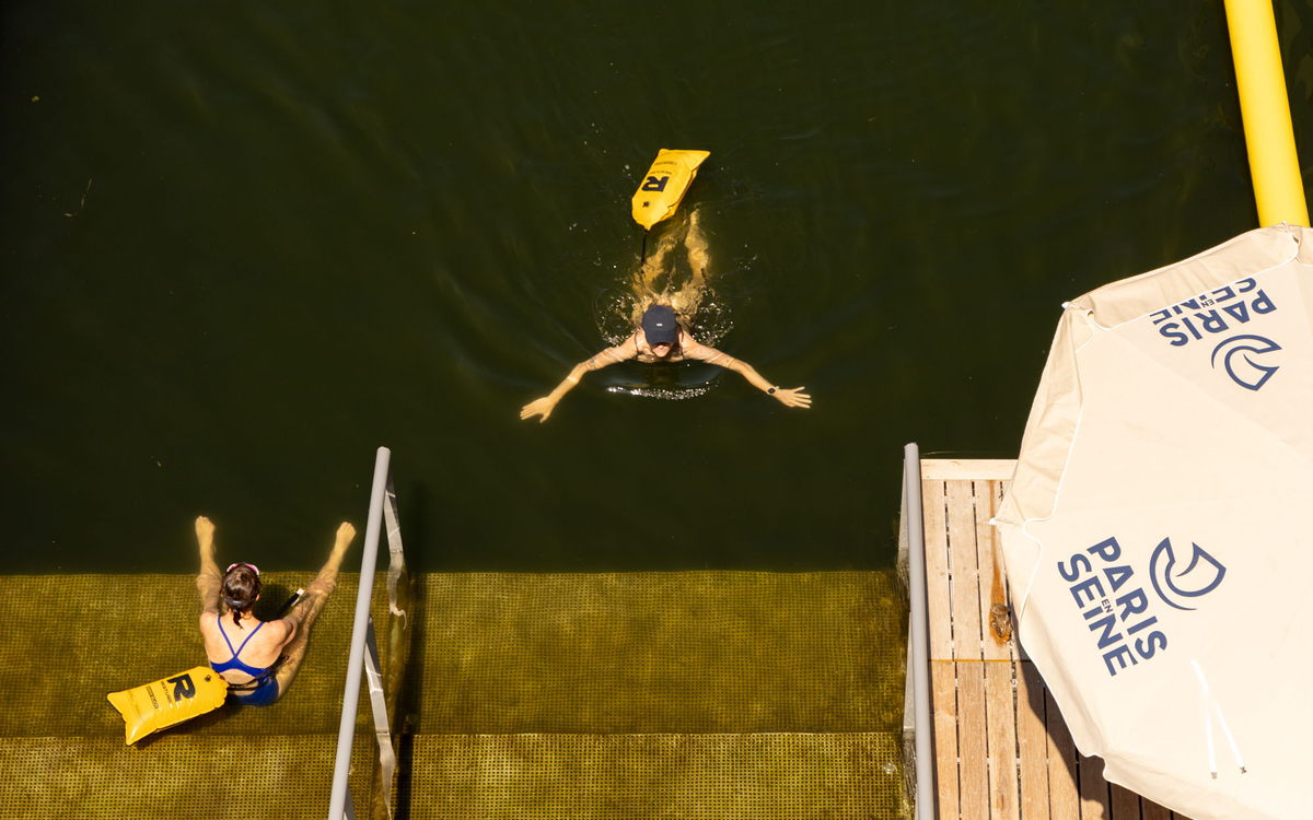 Photo prise d'en haut montrant une femme en train de nager et une autre assise au bord du bassin avec les jambes dans l'eau