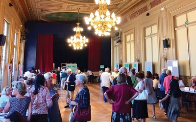 Assemblée Générale des Familles du 6e arrondissement avec des personnes qui sont dans la Mairie et qui discutent inscription.