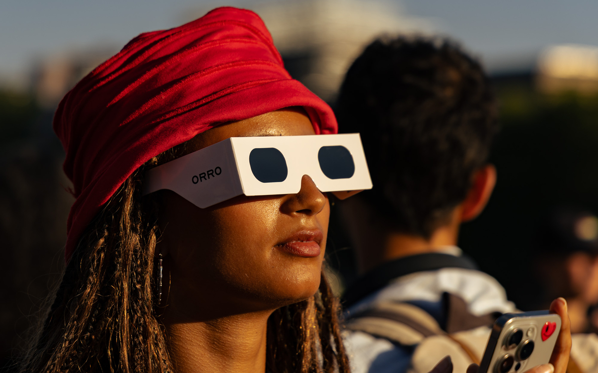 Une personne portant les lunettes de protection anti UV en train de regarder l'éclipse.