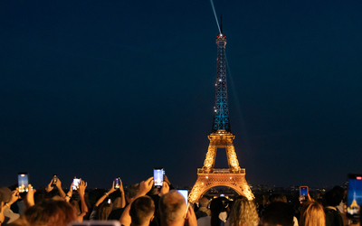 Des personnes photographient Tour Eiffel illuminée aux couleurs de l'Ukraine à l'occasion de la fête nationale ukrainienne.