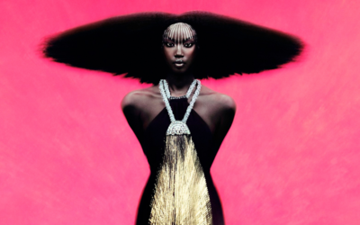 Une mannequin vêtue d'une tenue noire et dorée pose sur un fond rose bonbon.