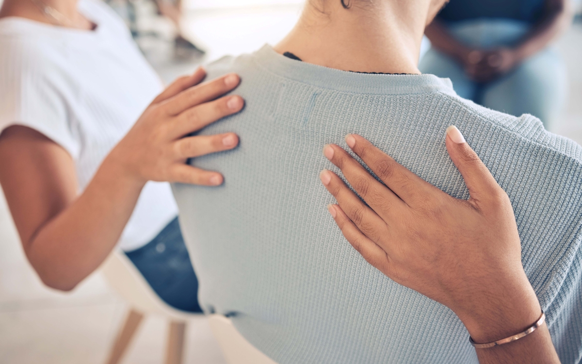 mains posées sur le dos d'une femme assise comme soutien