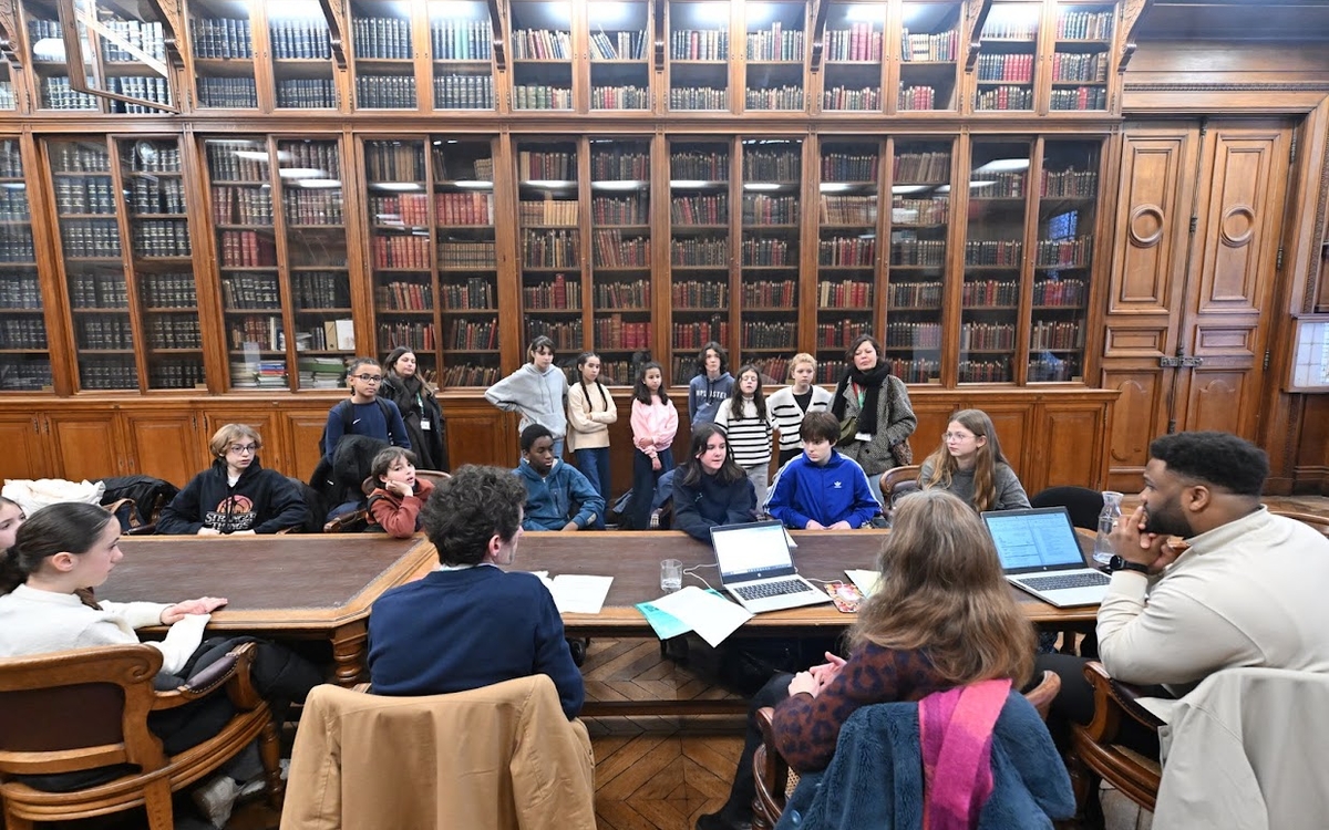 élèves et adultes autour d'une table dans la bibliothèque de l'hotel de ville