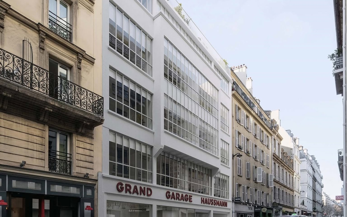 erspective du futur immeuble du 43-45 rue de Laborde : une façade blanche à grandes baies vitrées, avec l'inscription « Grand Garage Haussmann » au rez-de-chaussée.