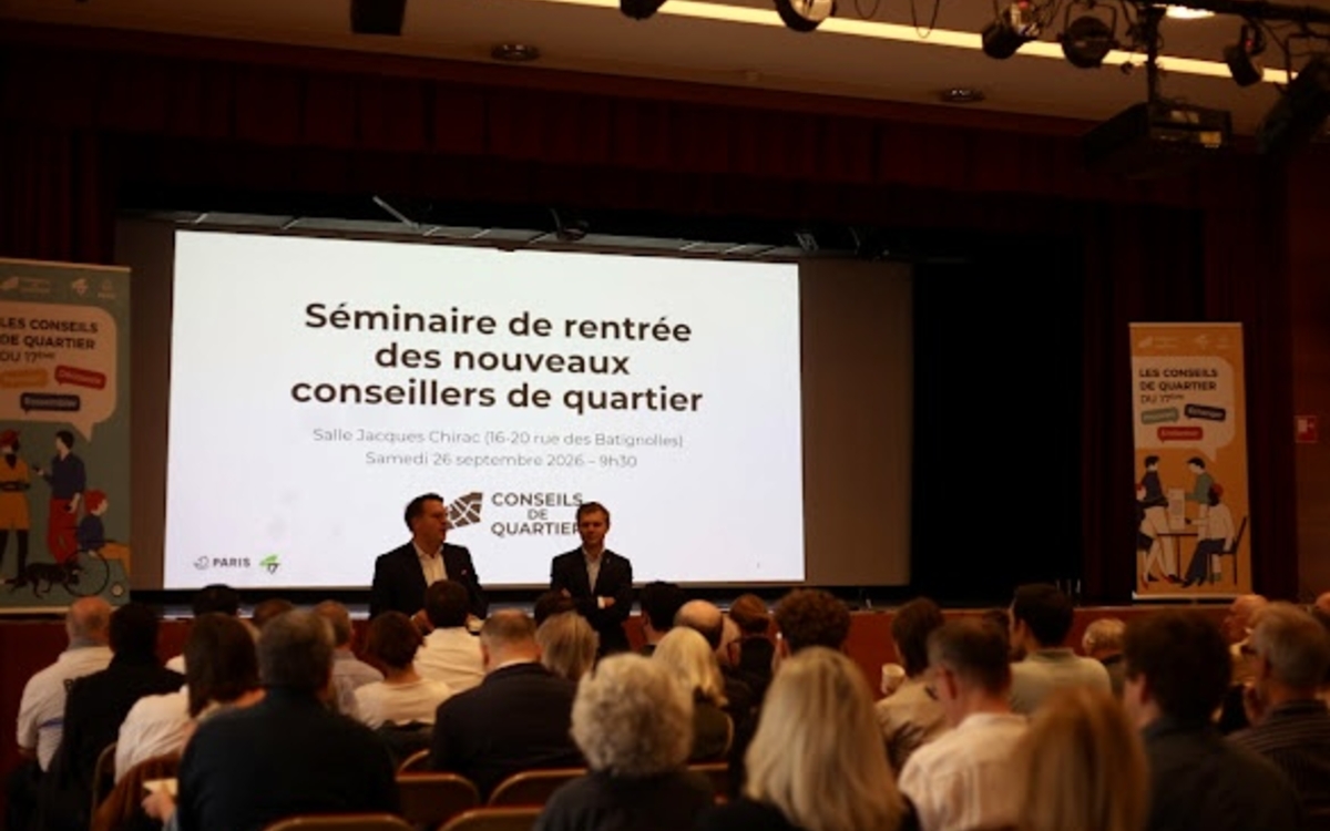 personnes assises dans une salle des fêtes écoutant le maire de l'arrondissement et son adjoint 
