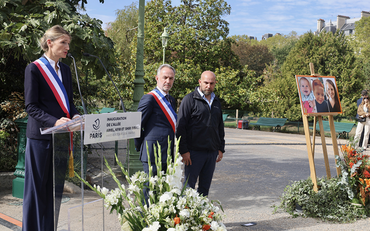 Une personne en écharpe tricolore prend la parole dans un parc 