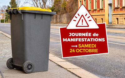 Photographie d'une poubelle jaune se trouvant à gauche de l'image. Elle est déposée sur un trottoir dans une rue. La rue est déserte et il n'y a aucune voiture sur la route. A droite de l'image se trouve un petit texte signifiant "Journée de manifestation, samedi 24 octobre" accompagné d'un panneau attention.
