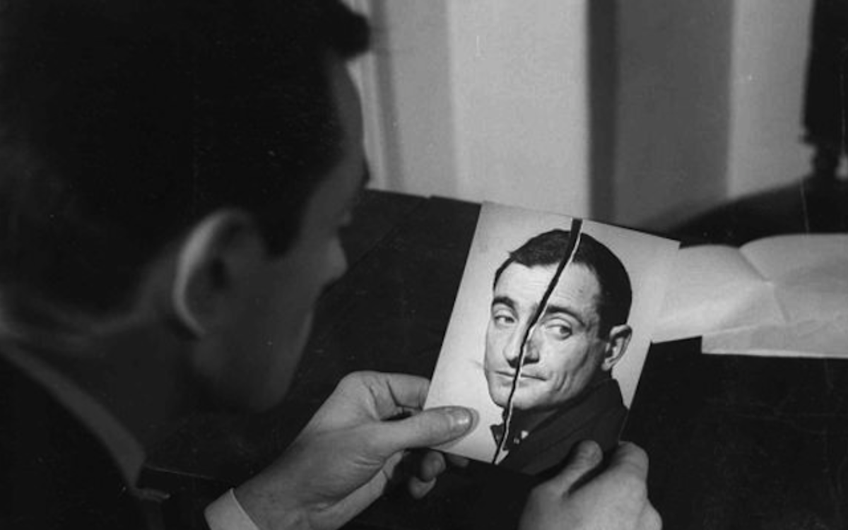 Un homme découpe un portrait photographique d'un autre homme avec une paire de ciseaux