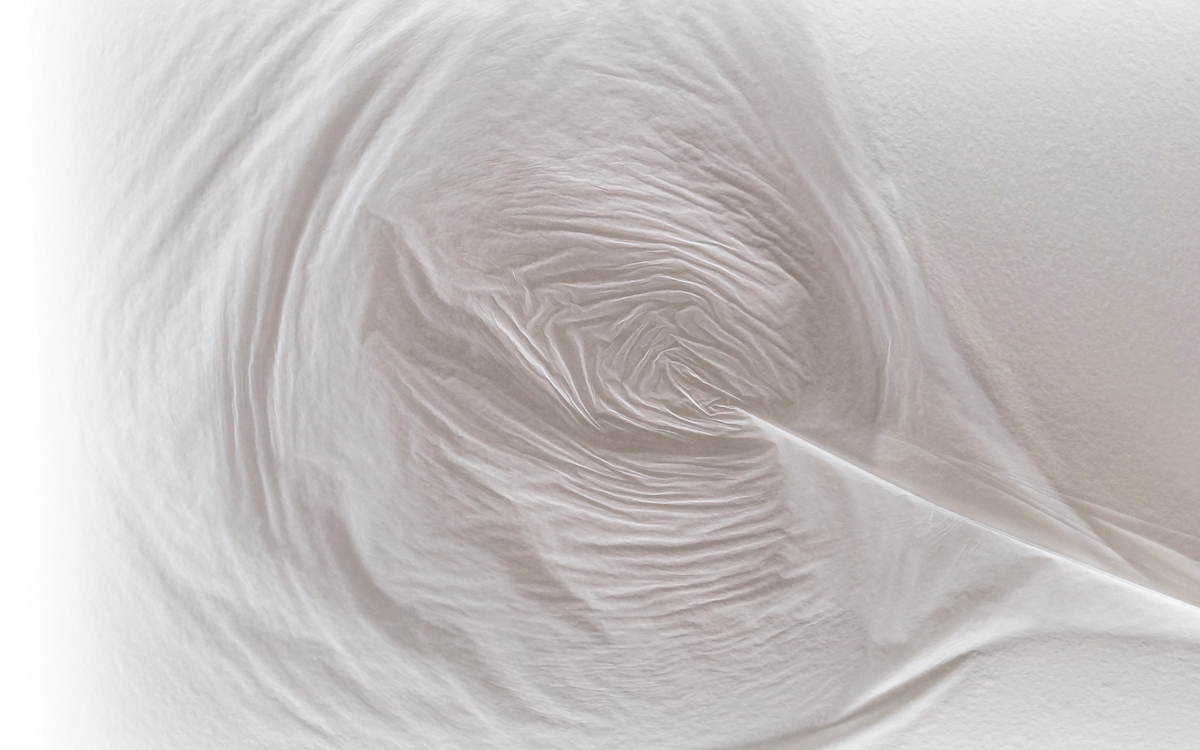 Vague de plis sur textile blanc.
