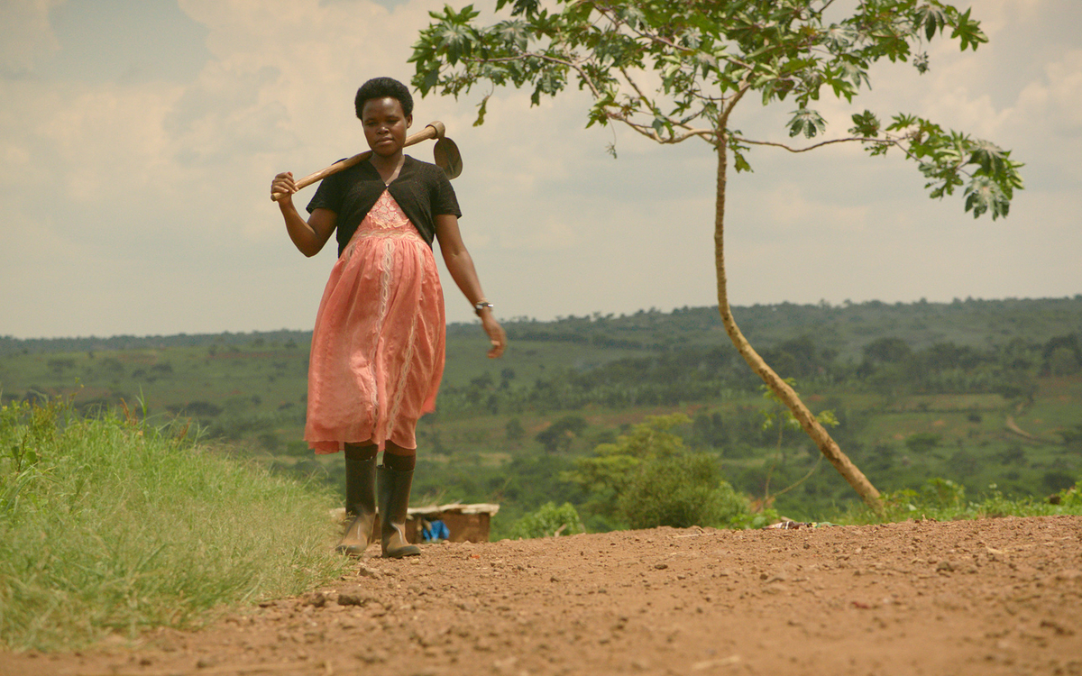 Jeune femme marchant, un outil agricole sur l'épaule