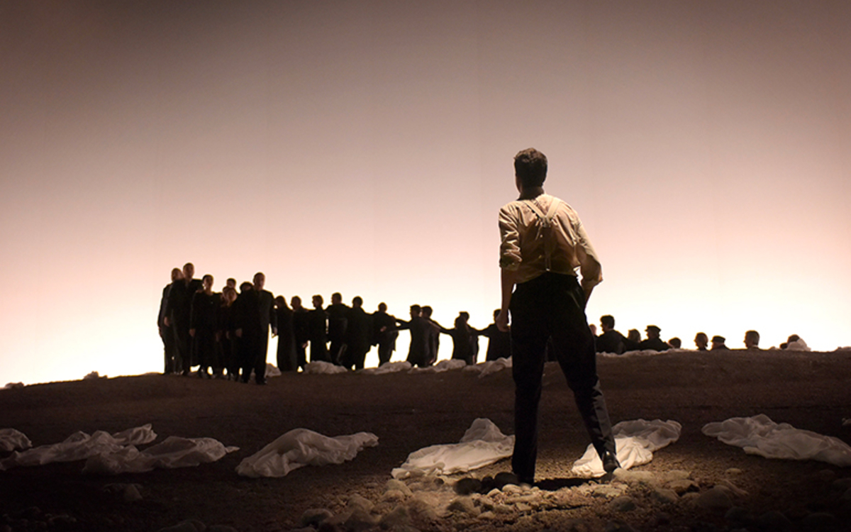 plan d'ensemble de la scène. Orphée dos au spectateurs et face à un groupe. 