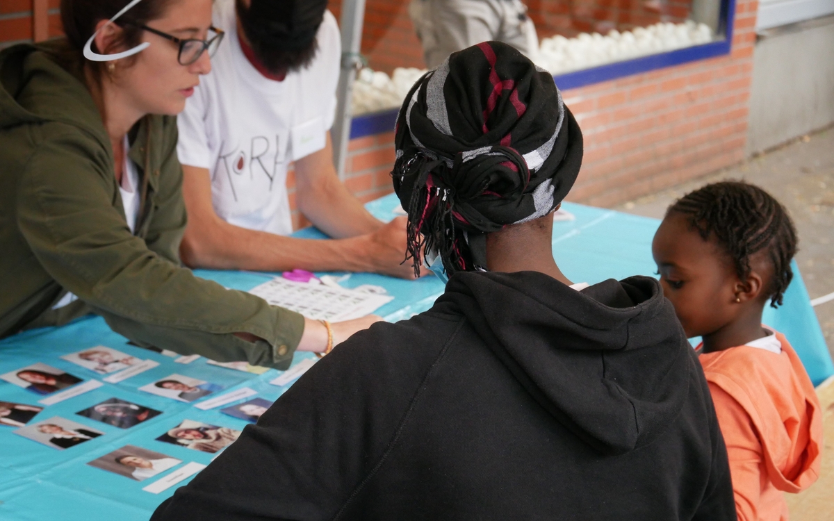 Une adulte et une enfant jouent à un jeu sur les discriminations, animé par des animateur·rices de l'association Korhom.