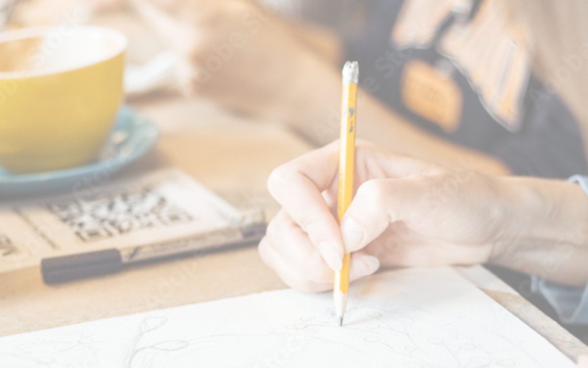 Une personne tient un crayon à papier et dessine sur du papier blanc