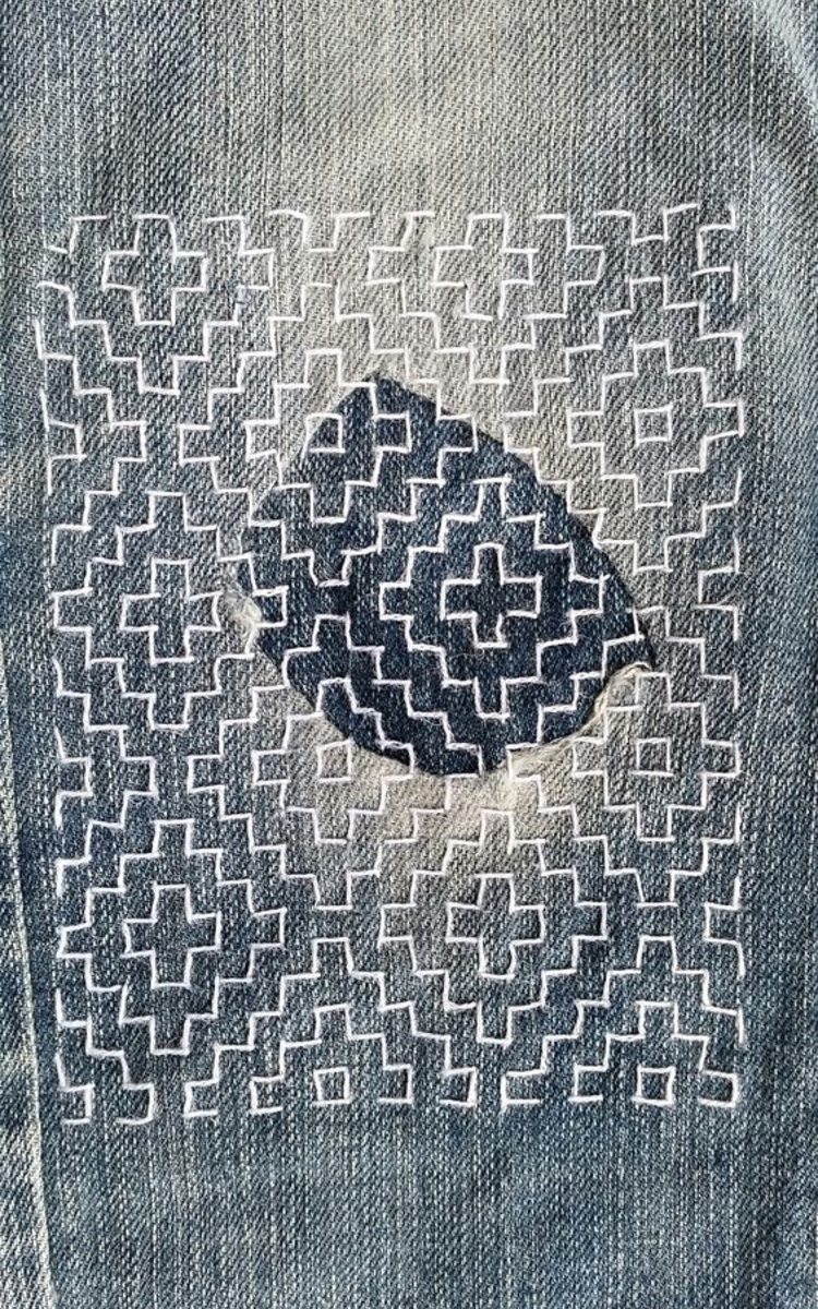 Jean reprisé par une broderie géométrique 
