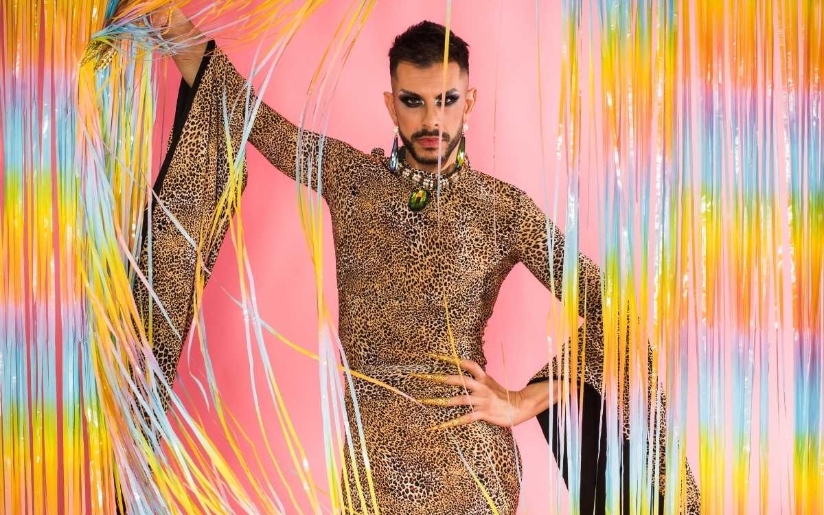 Une drag queen prend la pause derrière un rideau de perle