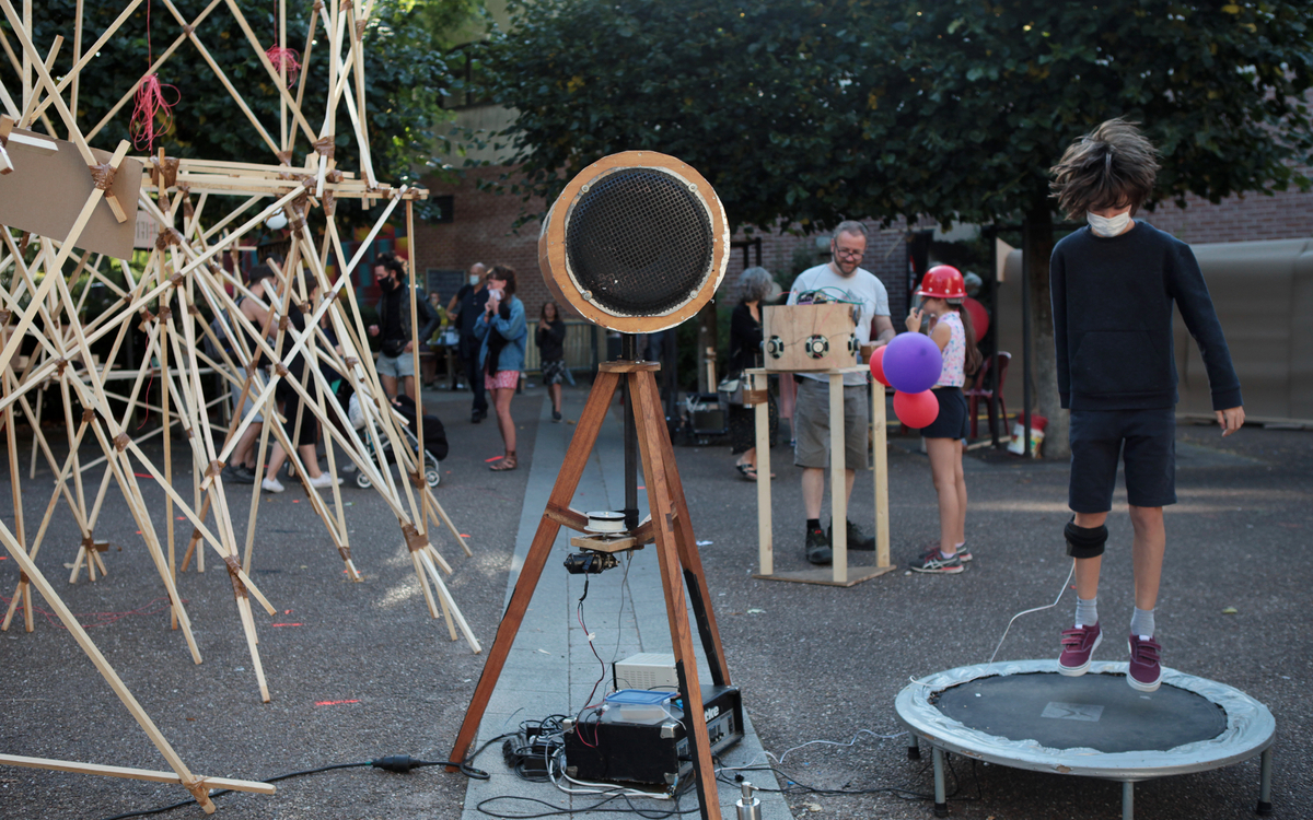 Structure improvisée en bois, haut-parleur bricolé, et trampoline sonore.