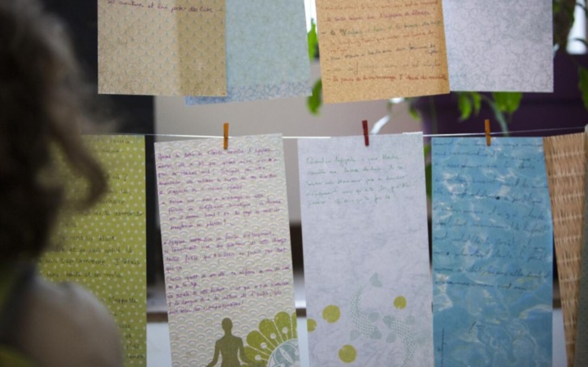 Des feuilles de papier sur lesquelles sont écrits des textes sont suspendus sur des fils.