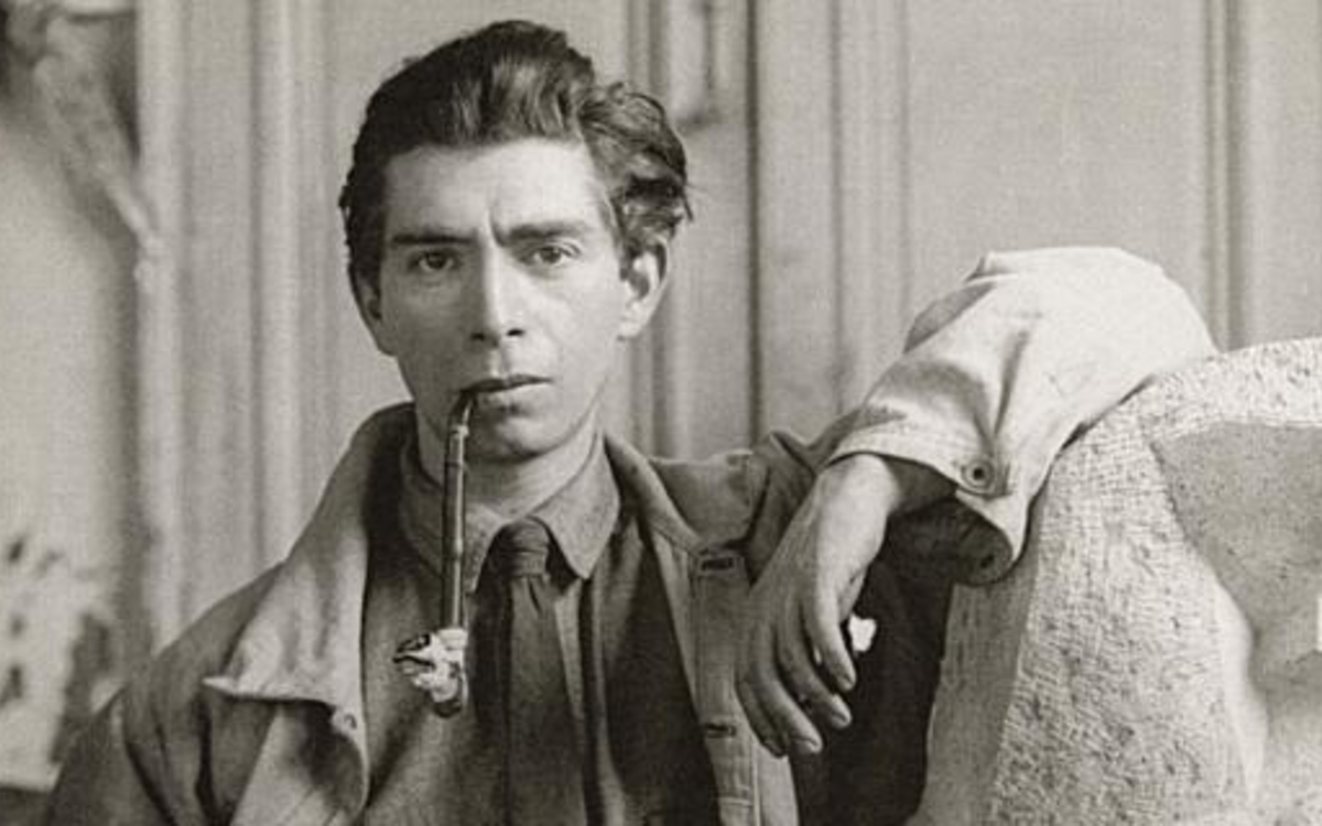 Ossip Zadkine, le coude appuyé sur une de ses scultptures.