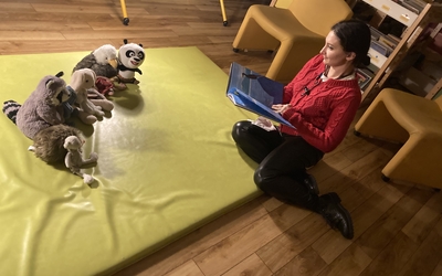 Une bibliothécaire lit un livre à des peluches installées en demi-cercle