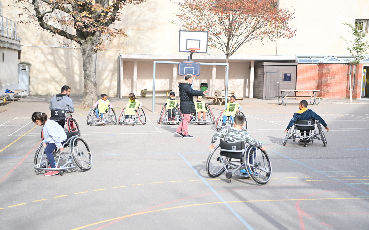 Jeu de ballon en fauteuil roulant dans une cour d'école parisienne 