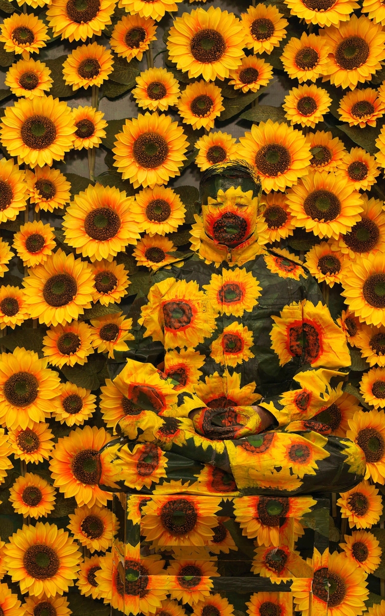 Photographie de Liu Bolin, Sunflower, taille medium, 2012,  taille de 120 x 120 cm représentant l'artiste dans un fond de tournesols en mise en abyme. 