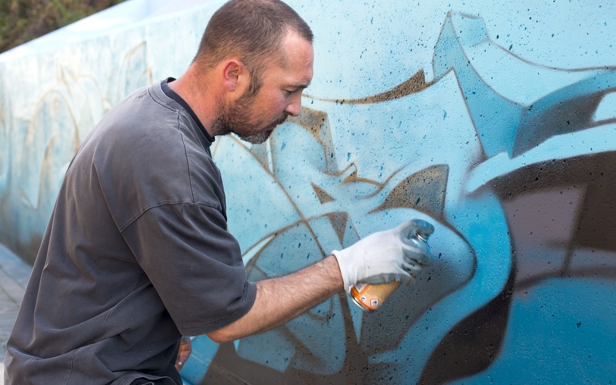 Fabien Girard alias Manyak, spécialiste de la perspective, graphe un mur en lettres bleues et noires 