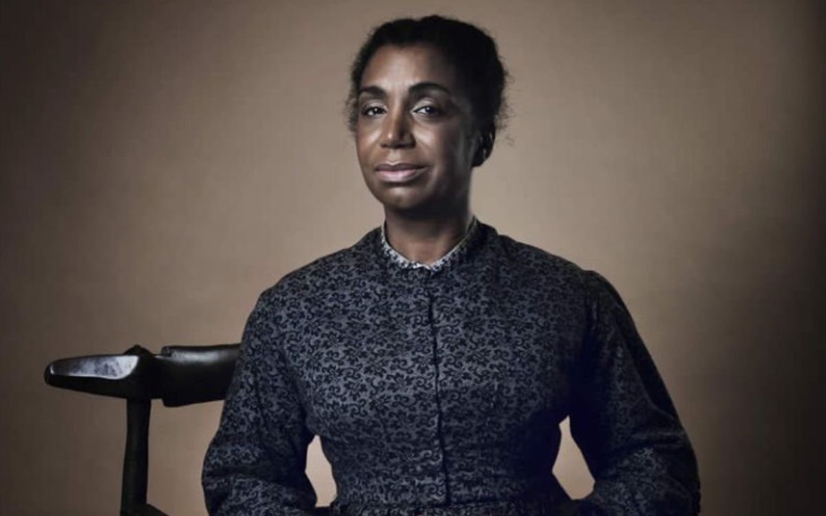 Souria Adèle, comédienne jouant le rôle de Mary Prince, pose sur fond marron. 