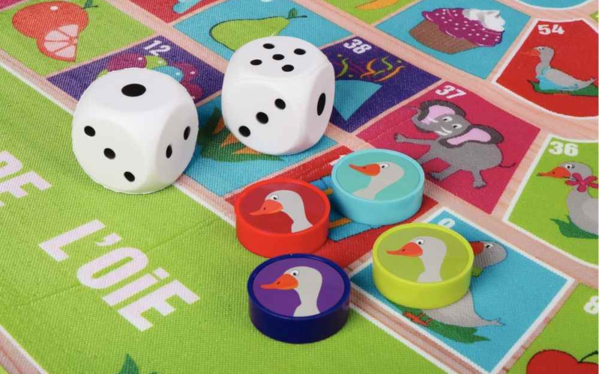 Petits dés blancs avec des petits jetons ronds en forme d'oie de couleurs violet / rouge / bleu sur un plateau avec des cases avec des dessins d'animaux