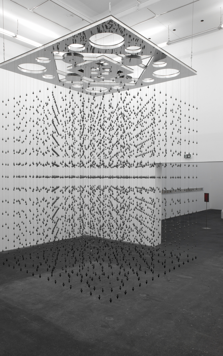 Œuvre Concrete Tears de l'artiste Melik Ohanian présentée au Mémorial de la Shoah dans le cadre de la Nuit Blanche 2023. Composées d'un mélange de ciment et de résine, 3451 larmes de béton sont suspendues grâce à des fils d'acier. L'ensemble est maintenu en lévitation grâce à une structure ajourée en inox miroitant. Le motif décoratif découpé en creux dans le métal évoque ceux des céramiques orientales.