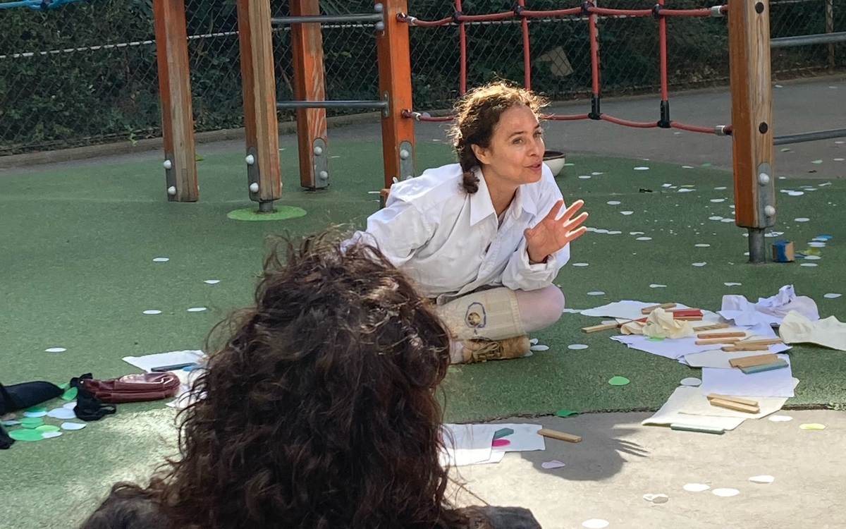 Une jeune fille assise en tailleur raconte son histoire au public.