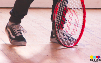 enfant avec une raquette de tennis, on ne voit que ses pieds et le haut de la raquette.