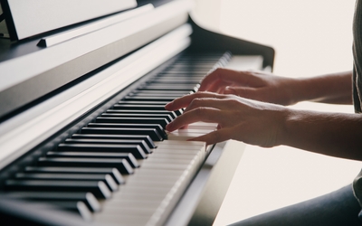 une personne qui joue sur un piano droit a deux mains 